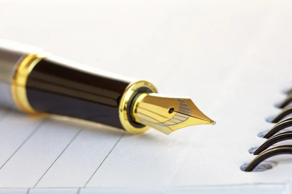 Fechar um bico de caneta de fonte de ouro em um bloco de notas — Fotografia de Stock