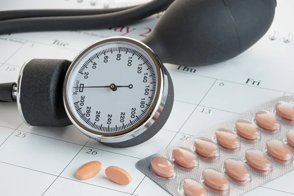 Tabletten en bloeddruk Meter op een kalender — Stockfoto