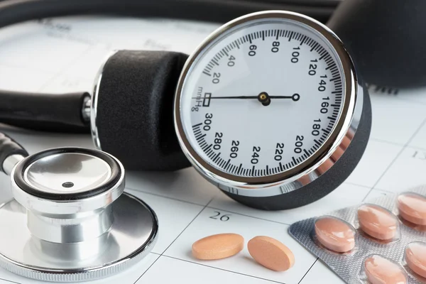 Tabletten en bloeddruk Meter op een kalender — Stockfoto