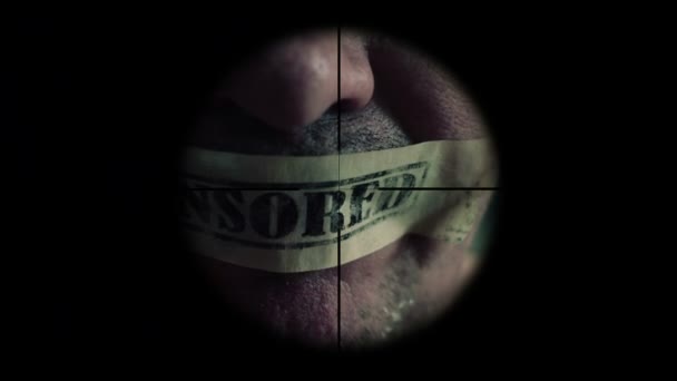 Sniper scope on man with tape censored over mouth — Stock Video