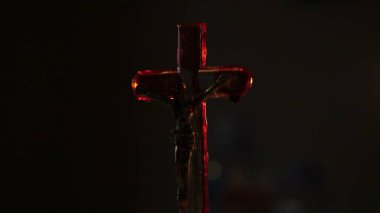 Close up of cross of jesus with blood lit by candle.	