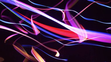 Siyah arkaplana karşı hareket eden renkli fiber dizgiler
