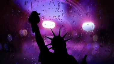 Yağmurlu bir pencereye yaslanmış, bulanık şehir ışıklarına sahip özgürlük heykeli.