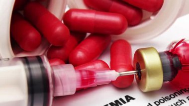 Tıbbi Şırınga kırmızı şişeden kan alıyor ve kağıt üzerinde kan zehirlenmesi uyarısı var.