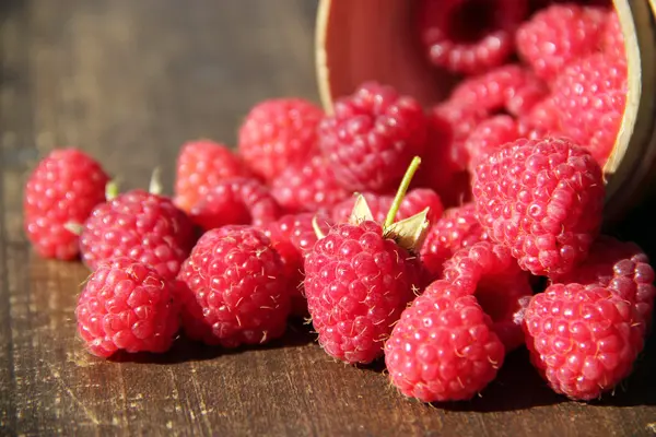 Reife süße Himbeeren in Schüssel auf Holztisch — Stockfoto