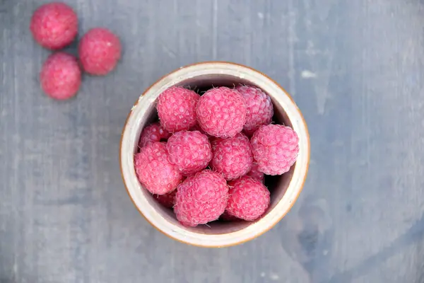 Reife süße Himbeeren in Schüssel auf Holztisch — Stockfoto