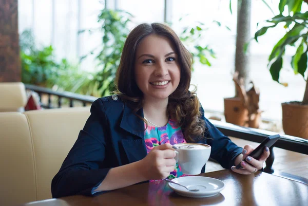 Güzel genç kız kahve içiyor.