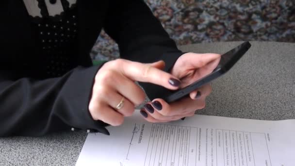 Дівчина дивиться через повідомлення по телефону — стокове відео