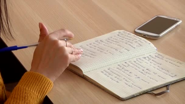 Vrouwelijke hand schrijven in een notitieblok — Stockvideo