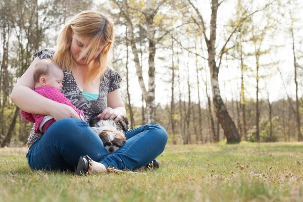 Mother with puppy and baby on the grass — Stock Photo, Image