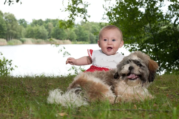 Bébé et chiot heureux près du lac — Photo