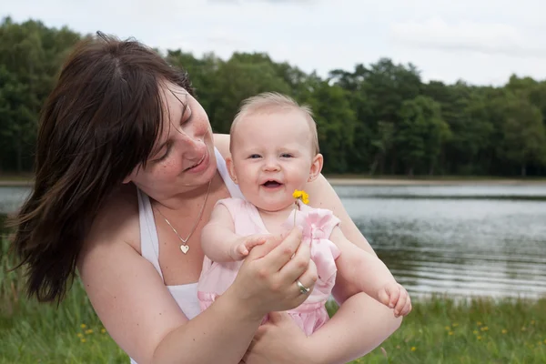 Smiling mother with her baby and the flower — Stock Photo, Image