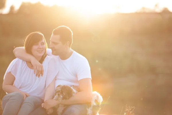 Junges Paar und Welpe im Sonnenlicht — Stockfoto