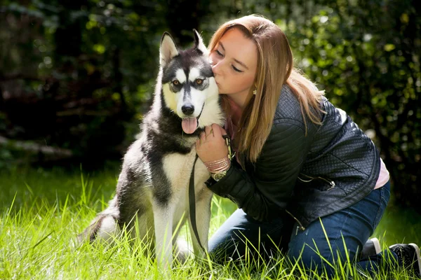 Fille est assis avec son chien dans l'herbe — Photo