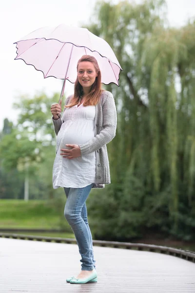 Pregant žena venku s deštníkem — Stock fotografie