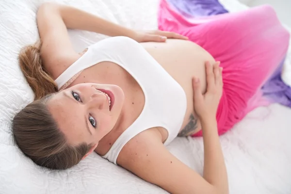 Mujer embarazada sonriente en su cama — Foto de Stock