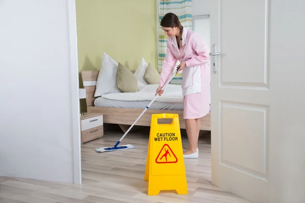 Kvinnlig hushållerska rengöring golv — Stockfoto