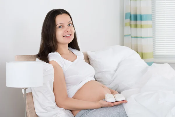 Gravid kvinna anläggning små skor — Stockfoto