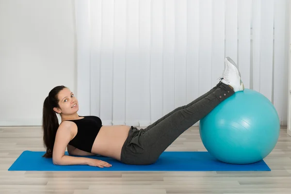 Jovem grávida do sexo feminino fazendo exercício — Fotografia de Stock