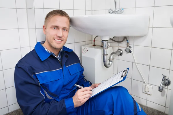 Klempner schreibt auf Klemmbrett — Stockfoto