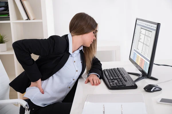 Mujer de negocios con dolor de espalda en la silla — Foto de Stock