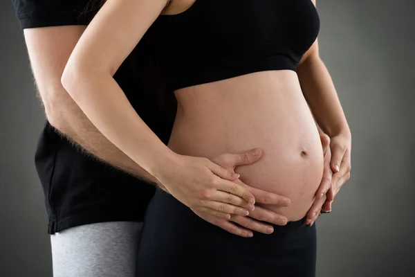 Mužské ruce nad těhotné bříško — Stock fotografie