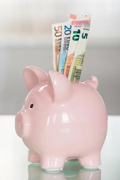 Piggybank con billetes en euros en la mesa — Foto de Stock