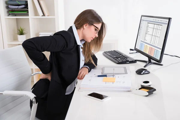 Mujer de negocios con dolor de espalda en la silla — Foto de Stock