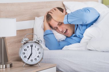 Sleeping Man with Ringing Alarm Clock clipart