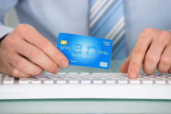 Empresário com cartão de crédito e teclado — Fotografia de Stock