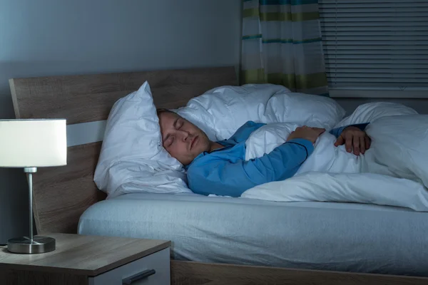 Молодой человек спит в спальне — стоковое фото