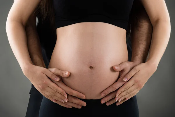 Manlig Hand över gravid kvinna mage — Stockfoto