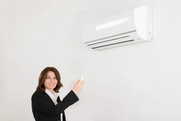 Businesswoman Operating Air Conditioner — Stock Photo, Image