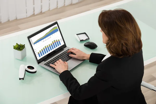 Geschäftsfrau analysiert Grafik auf Laptop — Stockfoto