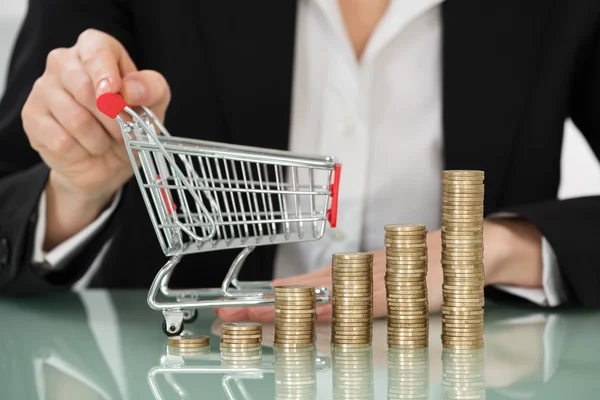 Carro de compras con monedas apiladas en el escritorio —  Fotos de Stock