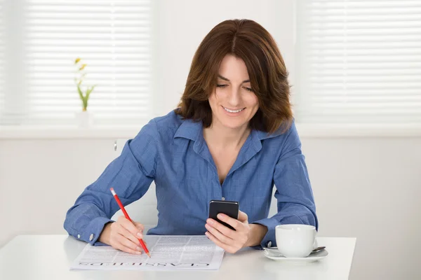 Frau liest Zeitung mit Smartphone — Stockfoto