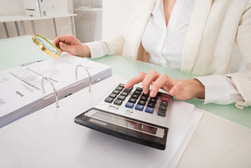 Close-up Of Businesswoman Checking Bill With Magnifying Glass