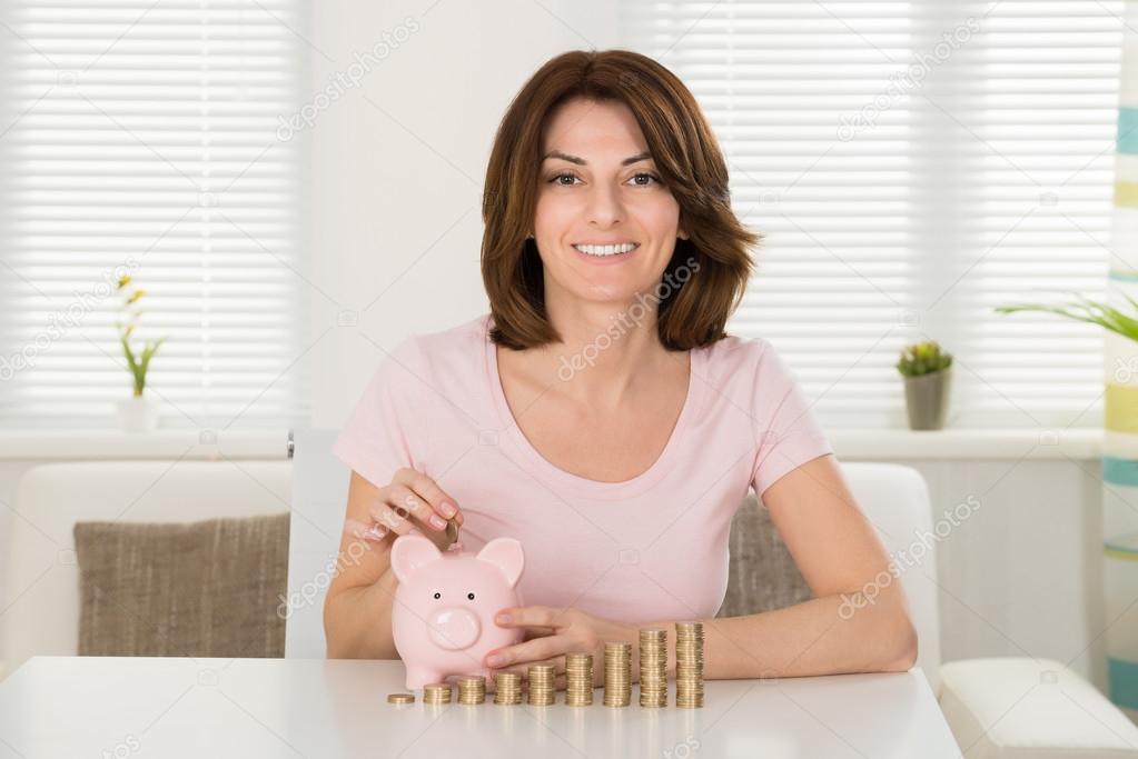 Woman Inserting Coin In Piggybank