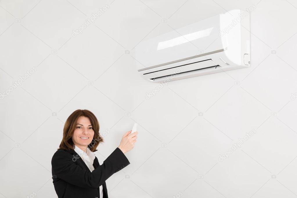 Businesswoman Operating Air Conditioner