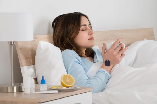 Mann sitzt auf Bett und trinkt Tee — Stockfoto