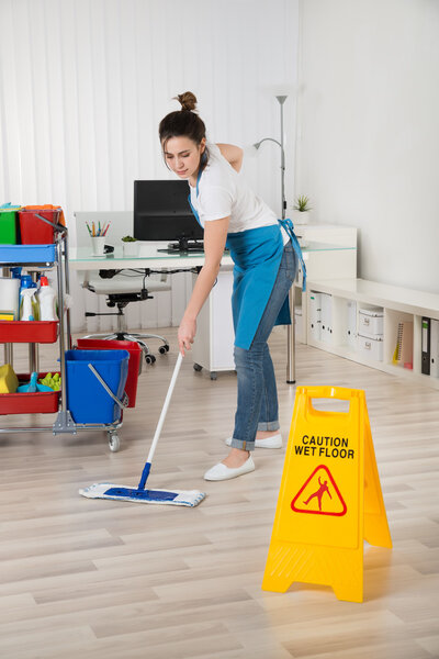 Уборщица моет деревянный пол
