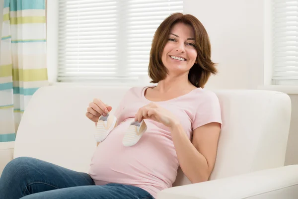 Zwangere vrouw met schoenen voor Baby Stockafbeelding