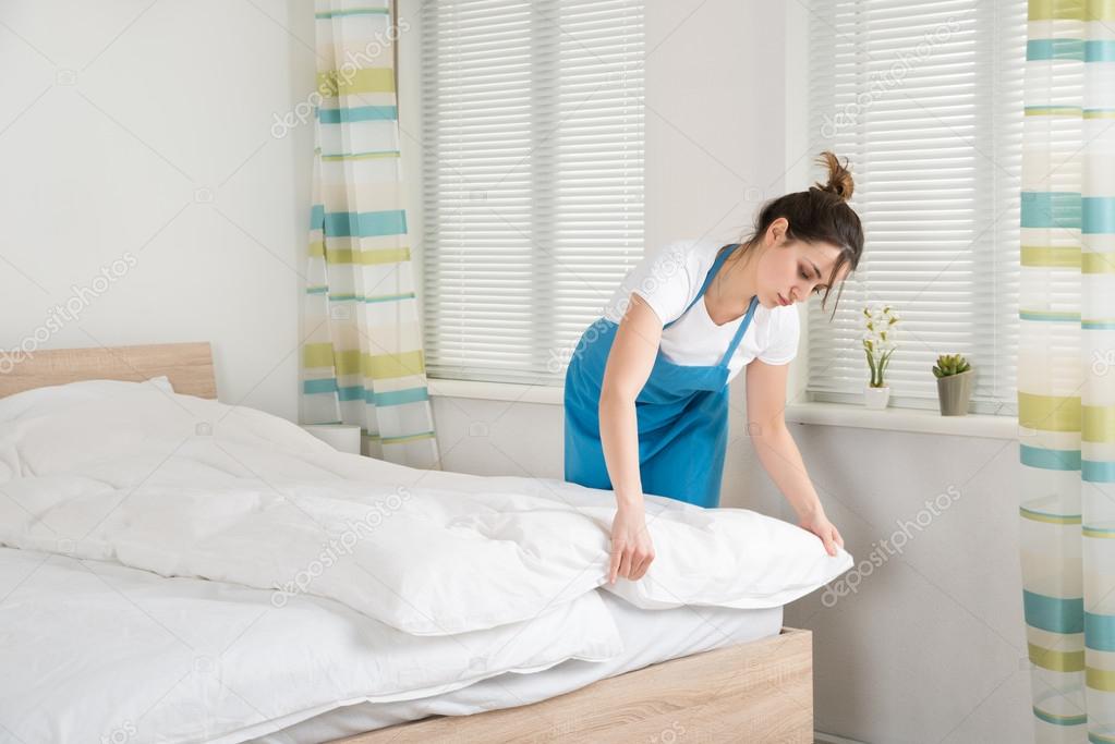 Female Housekeeper Arranging Bedsheet