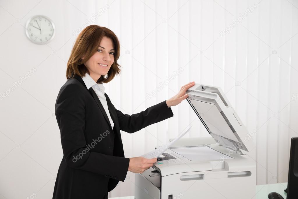 Businesswoman Copying Paper On Photocopy Machine