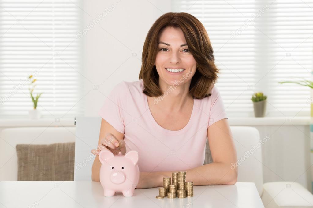 Woman Inserting Coin In Piggybank