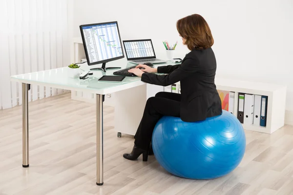 Mujer de negocios sentada en la bola de pilates — Foto de Stock