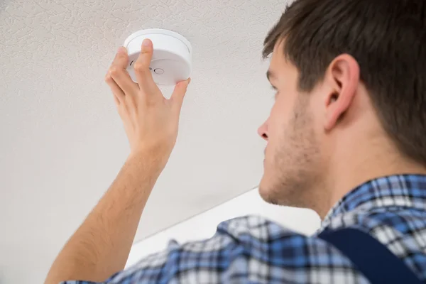 Eletricista masculino reparando sensor de incêndio — Fotografia de Stock