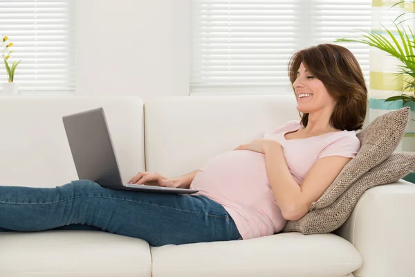 Mulher no sofá com seu laptop — Fotografia de Stock