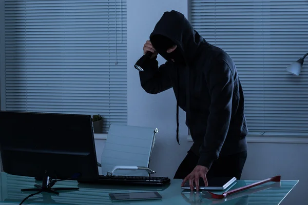 Robber avec lampe de poche dans le bureau — Photo