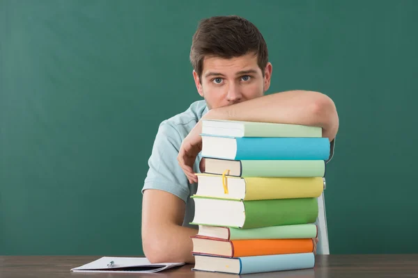 Jovem se apoiando na pilha de livros — Fotografia de Stock